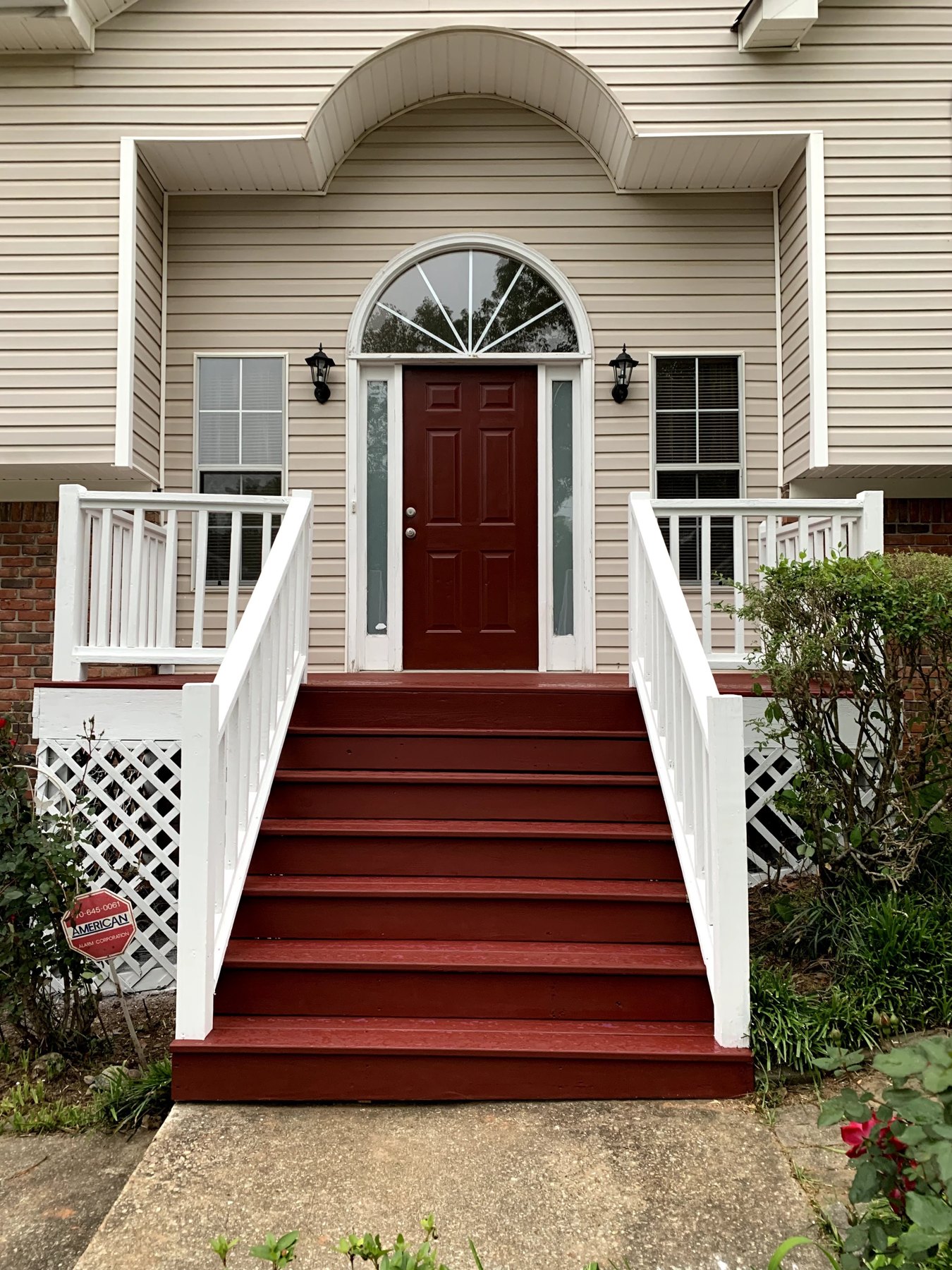 Deep red front door with matching painted steps and white railings